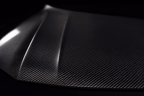 Nahaufnahme einer Motorhaube aus Sichtcarbon mit sichtbarer Faserstruktur