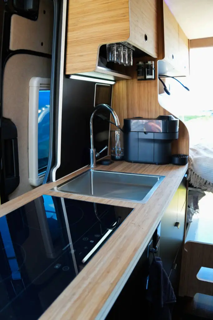 Kompakte Camper-Küche mit Induktionskochfeld, Spüle und Holzarbeitsplatte im MAN TGE 4x4